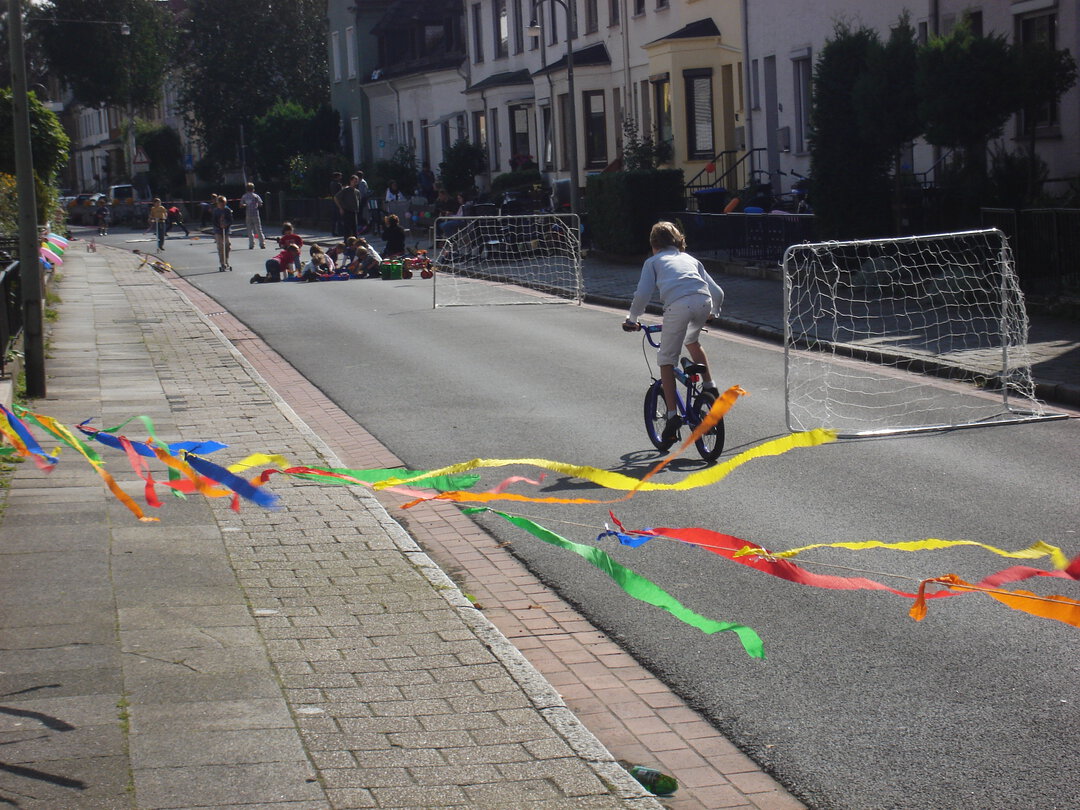 Ein BMX fahrendes Kind auf einer Spielstraße mit Fußballtoren